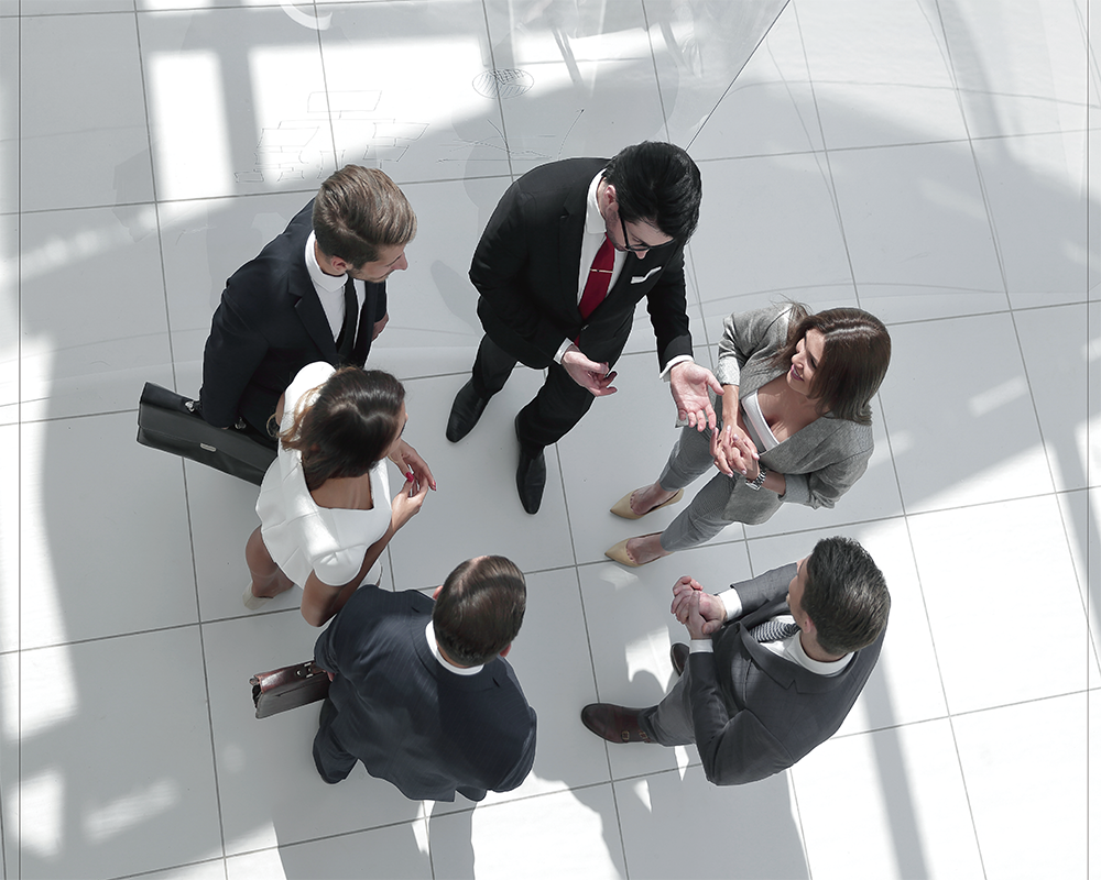 Aerial view of business people standing in a circle and talking on a white tile floor
